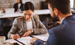 Woman signing paperwork at a desk during an employment contract meeting